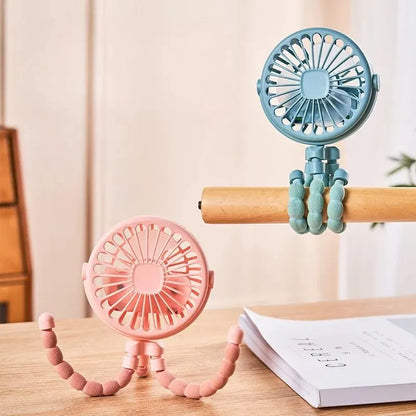 Two portable fans, one pink and one blue, on a wooden surface with a neutral background.
