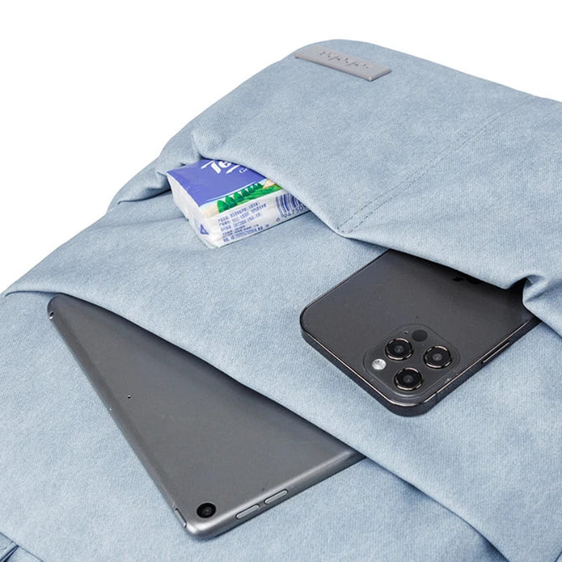 Light blue backpack with phone, tablet, and snack bar in front pocket on a white background