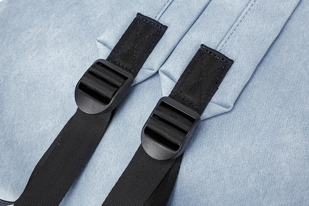 Two black straps with buckles on a light blue fabric background