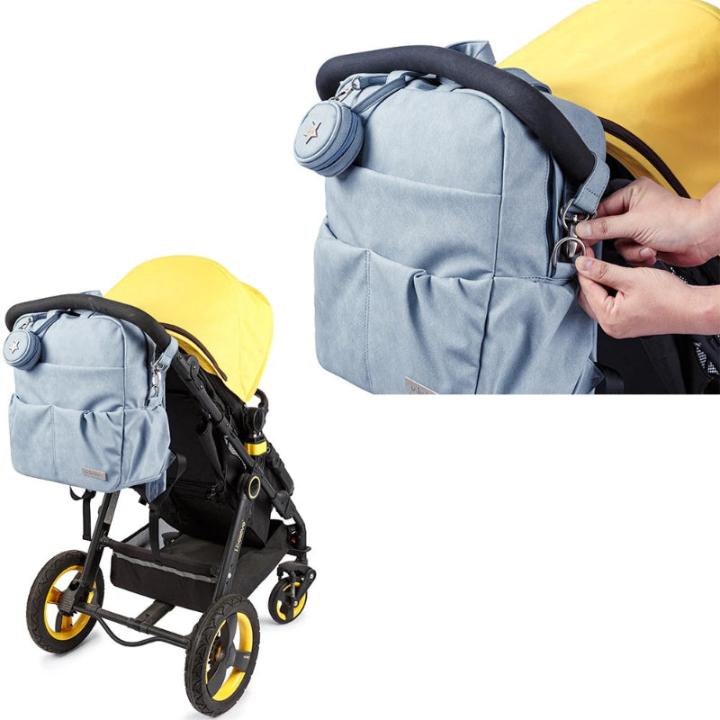 Light blue baby stroller with yellow accents and a matching backpack, showing a hand adjusting a strap.