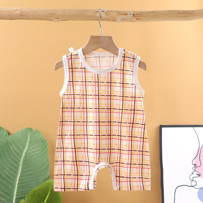 Plaid baby romper on a hanger against a yellow wall with a plant and framed picture.