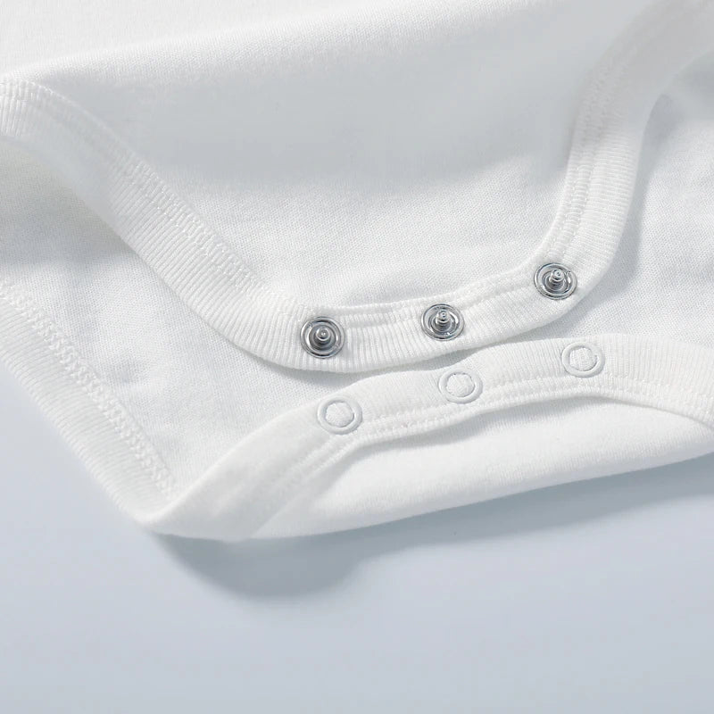 Close-up of a white baby onesie with button details on a light gray background