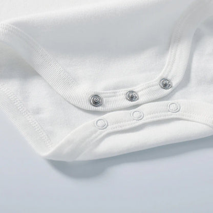 Close-up of a white baby onesie with button details on a light gray background