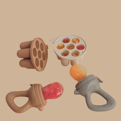 Baby feeding and snack tools including a fruit feeder, ice tray, and mesh bags on a beige background.